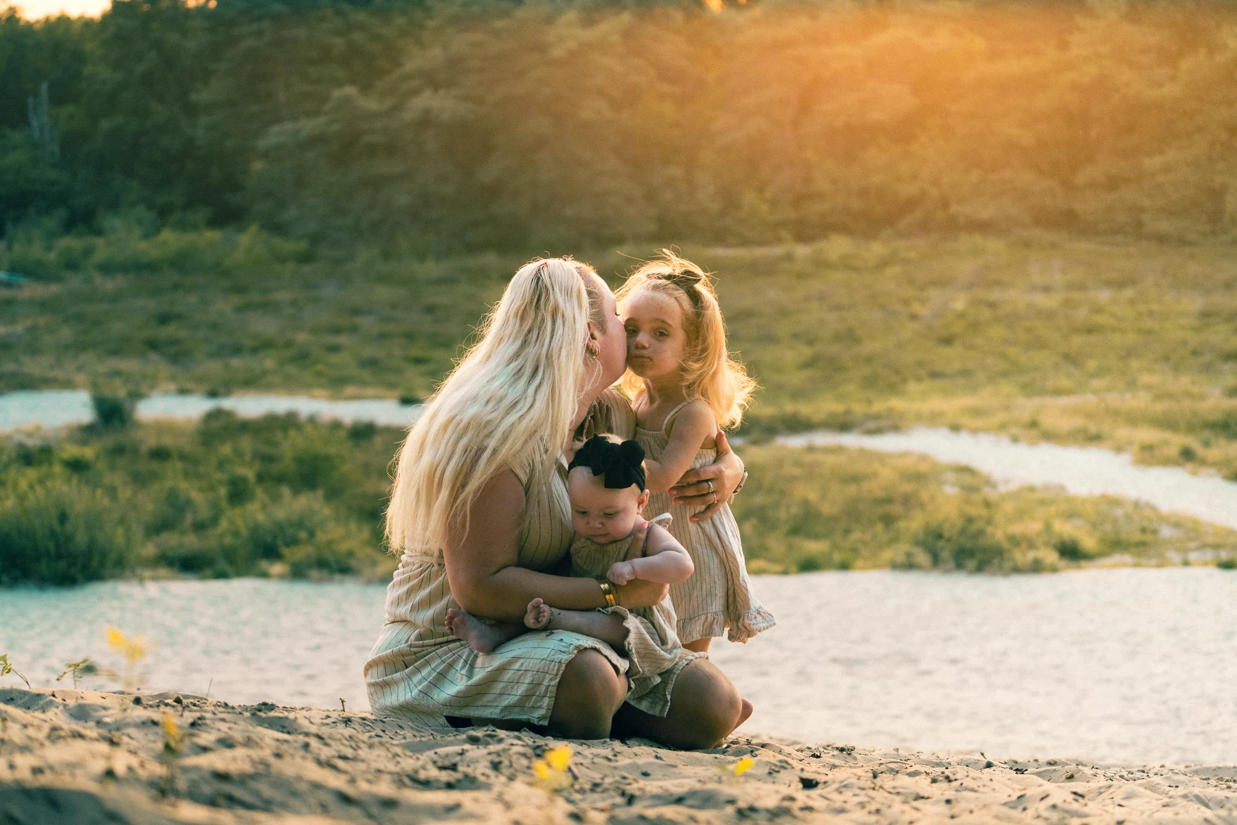 Een moeder zit met haar twee kinderen in het zand