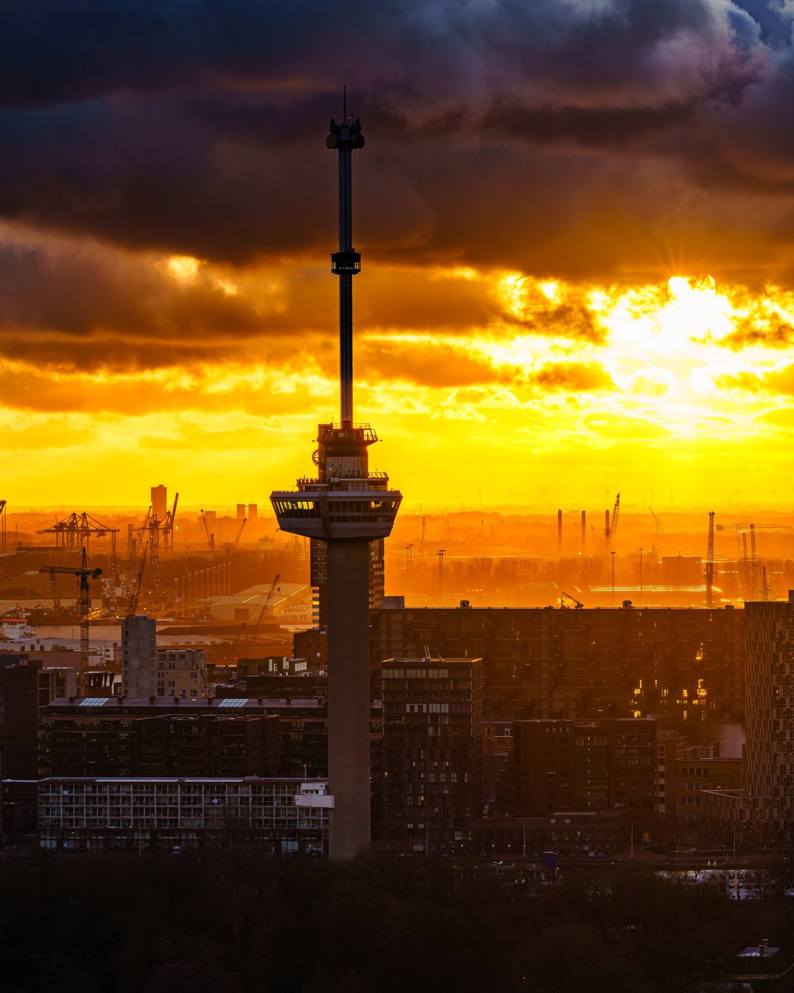 Euromast als silhouet tegen een oranje zonsondergang